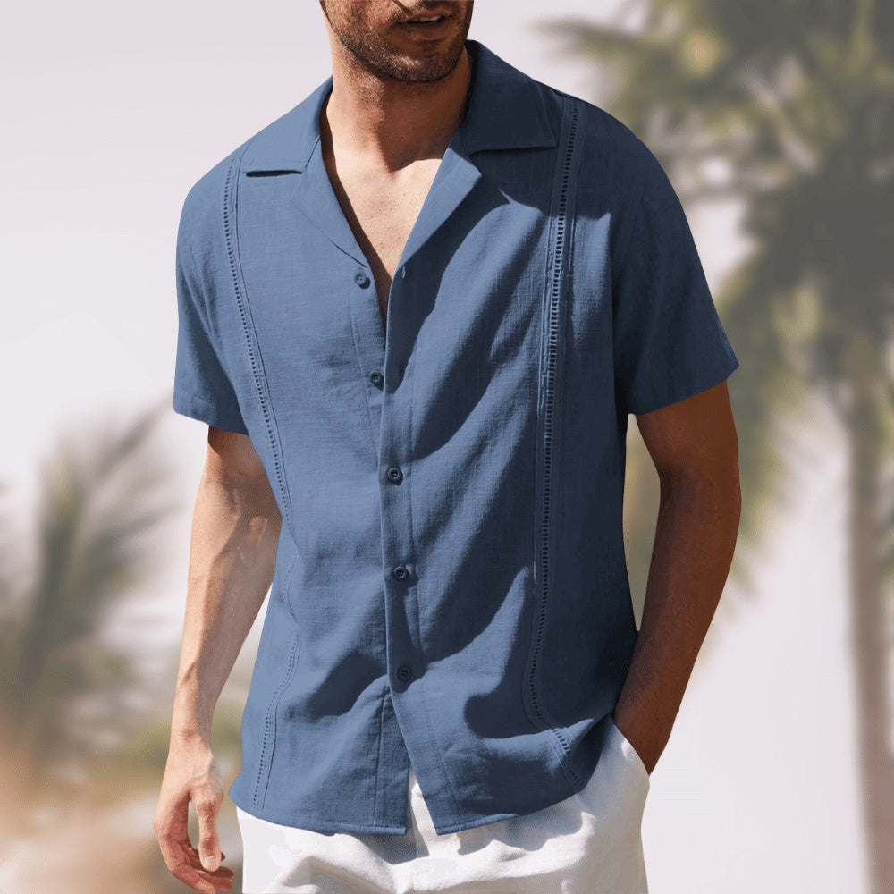 Man wearing a blue short-sleeve shirt with a blurred outdoor background