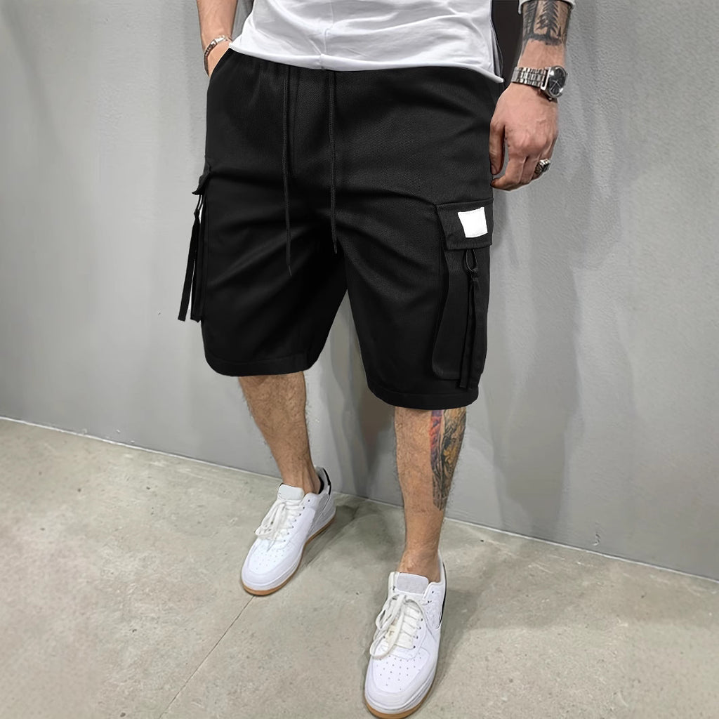 Person wearing black cargo shorts and white sneakers against a gray background