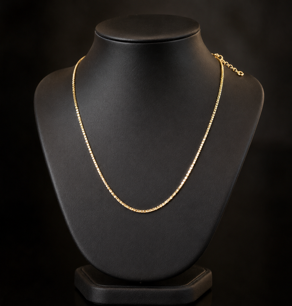 Gold necklace on a black mannequin bust against a black background