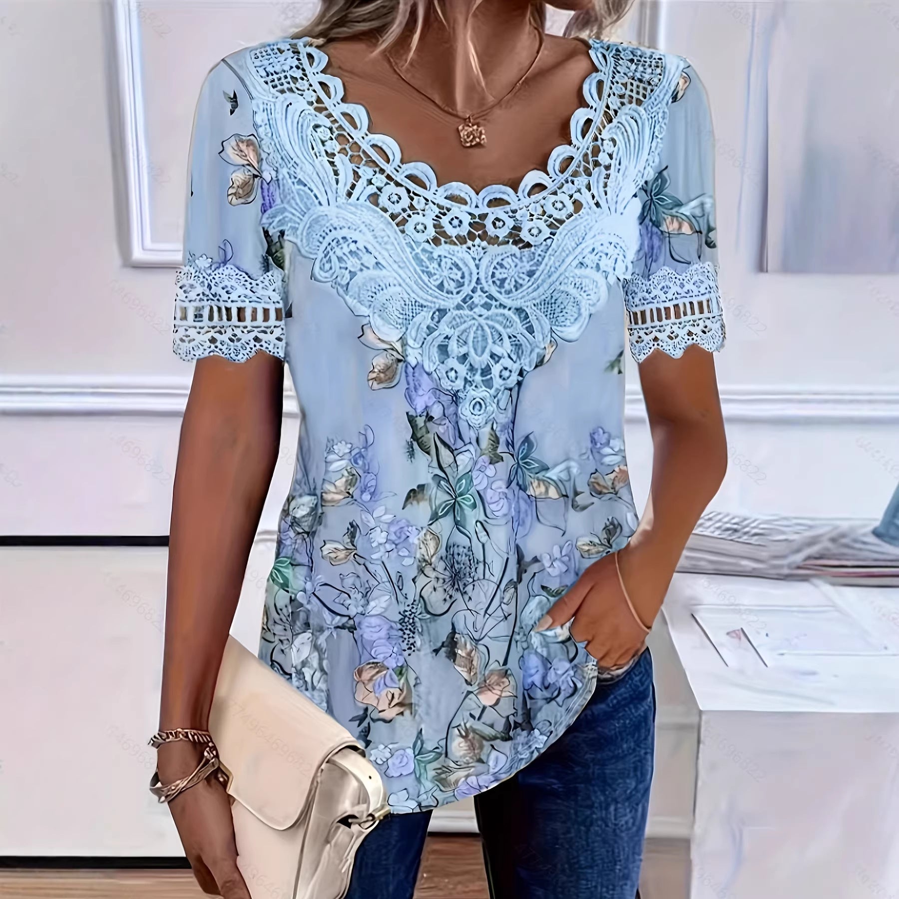 Woman wearing a light blue floral blouse with lace details in an indoor setting.