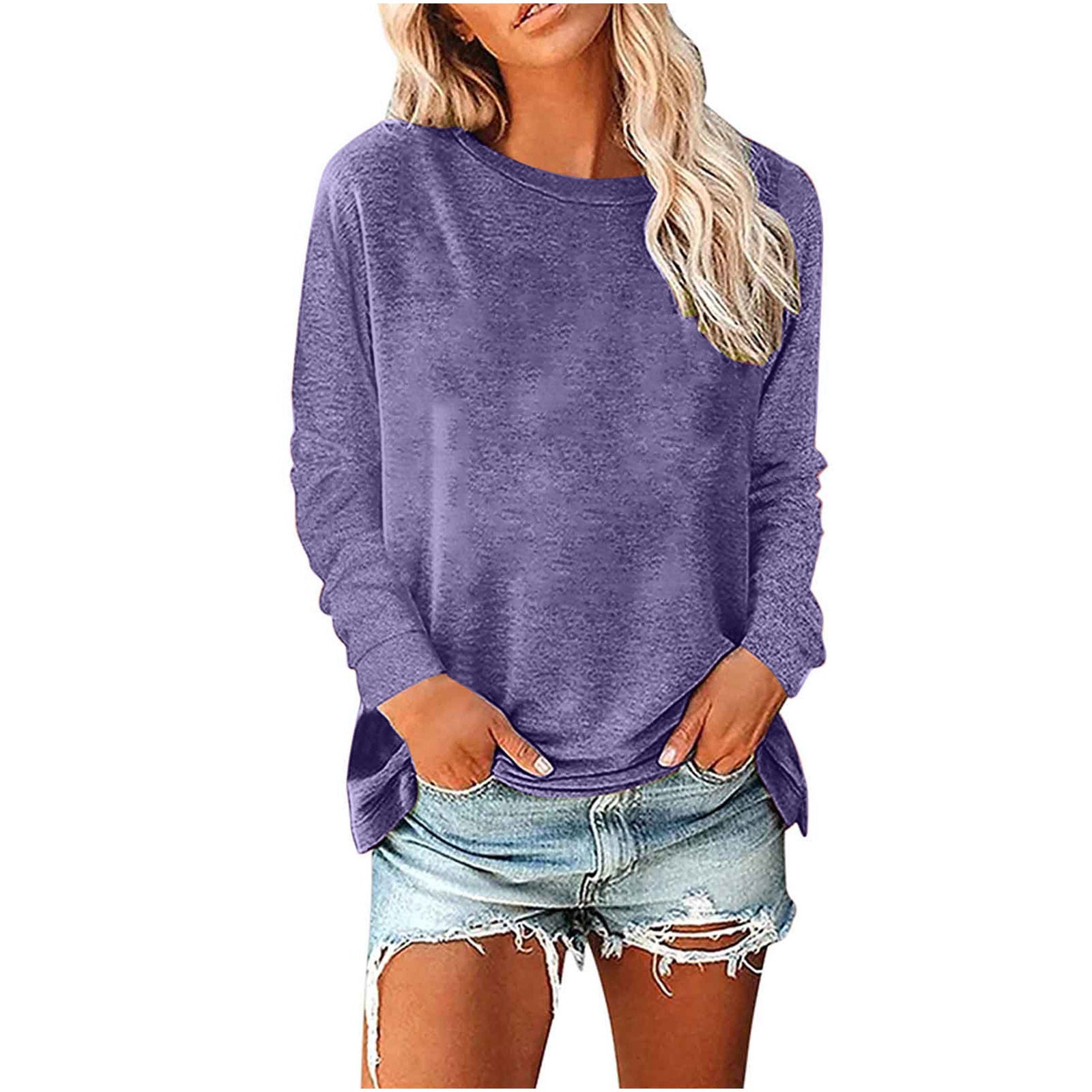 Woman wearing a purple long-sleeve top and denim shorts on a white background