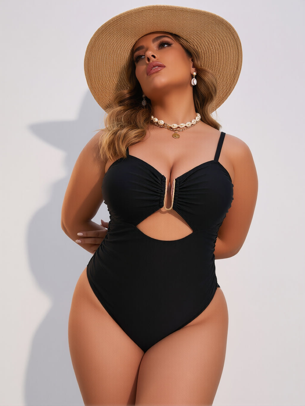 Woman wearing a black one-piece swimsuit and straw hat on a white background