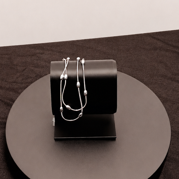 Black handbag with a strap on a round black platform against a white background