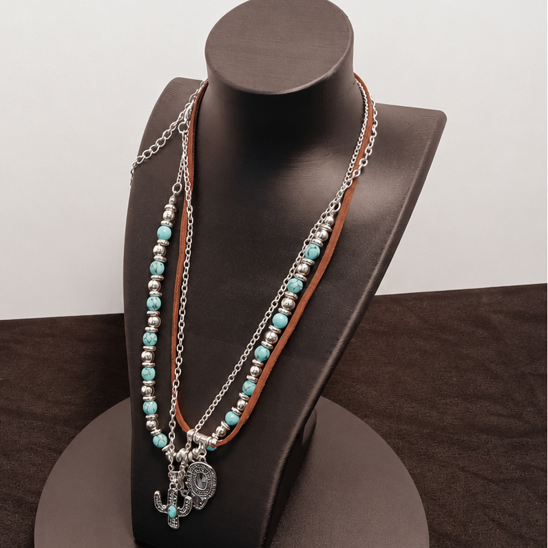Necklace with turquoise beads and a silver charm on a black stand against a white background