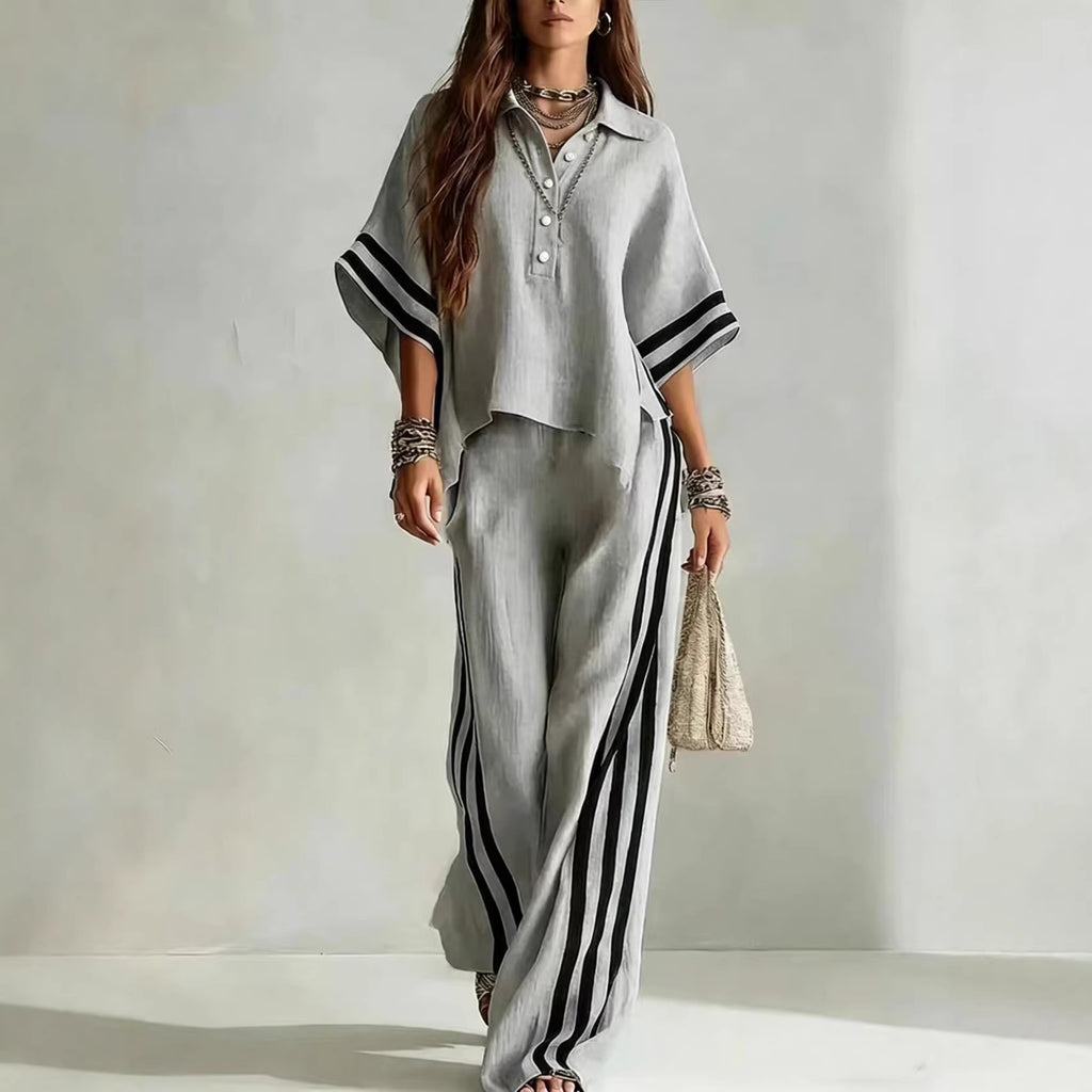 Woman wearing a gray outfit with black stripes on a plain background
