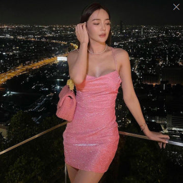 Woman in a pink dress standing on a balcony with a cityscape at night.