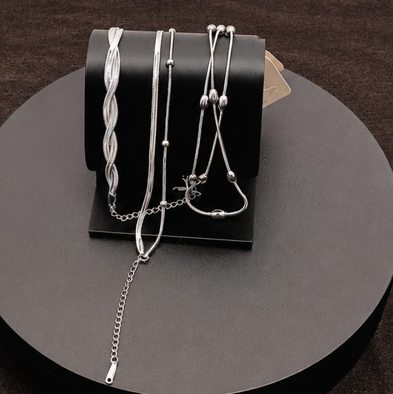 Jewelry set including necklaces and earrings displayed on a black stand with a white background