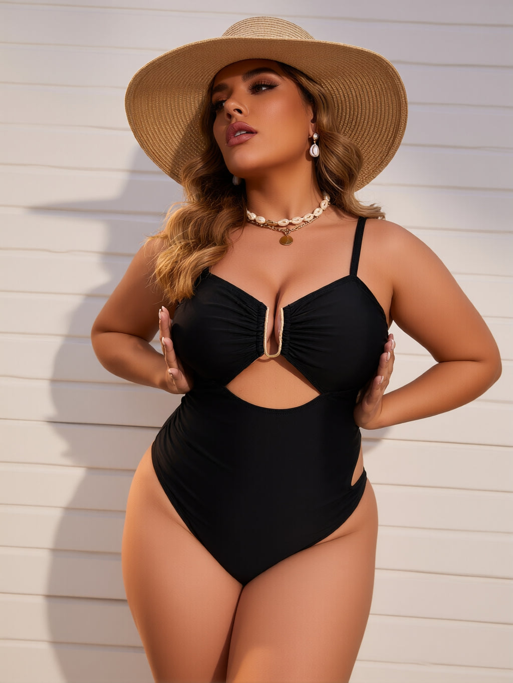 Woman wearing a black swimsuit and wide-brimmed hat against a light wooden wall.