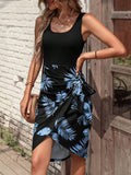 Woman wearing a black tank top and blue leaf-patterned skirt standing against a wooden wall.