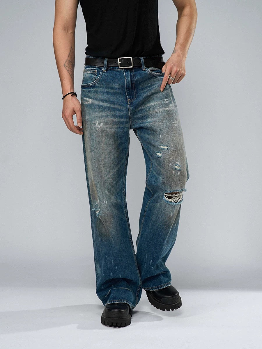 Person wearing distressed blue jeans on a plain background
