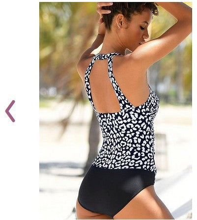 Woman wearing a black and white patterned swimsuit with blurred outdoor background