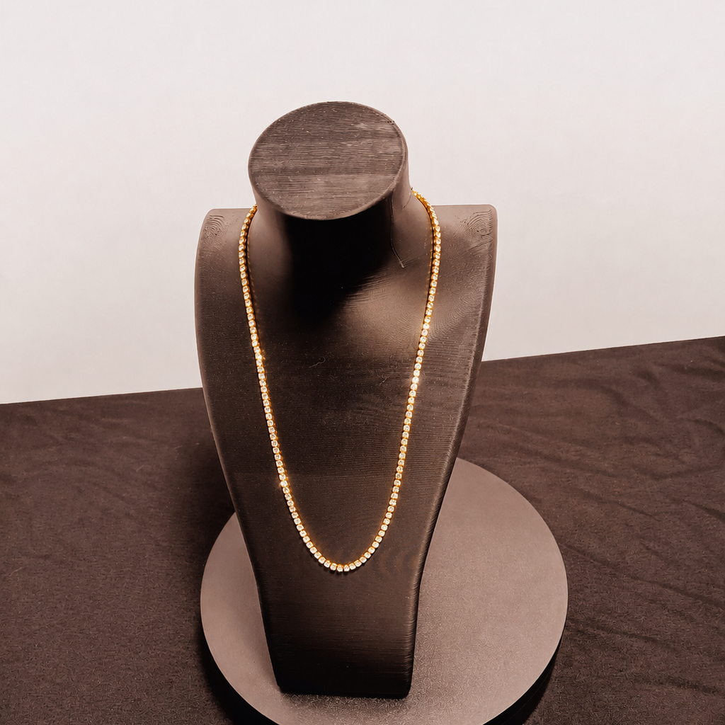 Gold necklace on a brown jewelry display stand against a white background