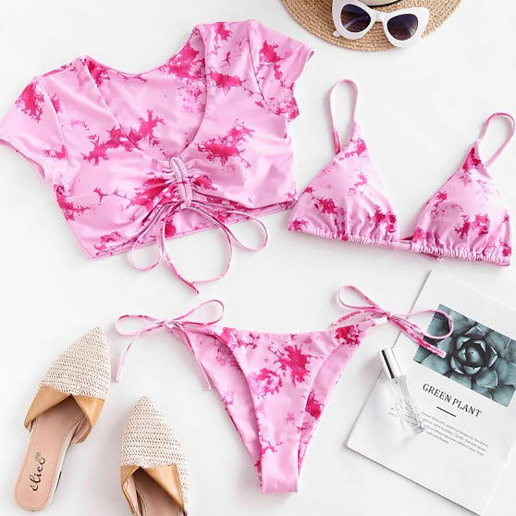 Pink  bikini set with matching top and bottom, sunglasses, sandals, and a magazine on a white background.