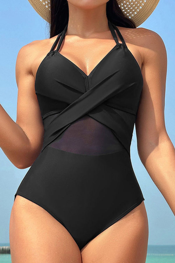 Woman wearing a black one-piece swimsuit with a straw hat against a clear blue sky.