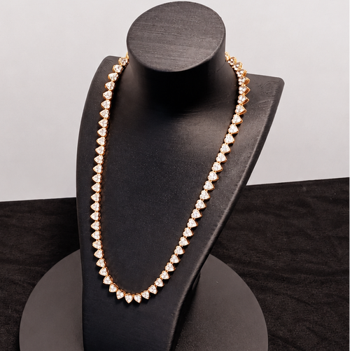 Gold necklace on a black jewelry stand against a white background