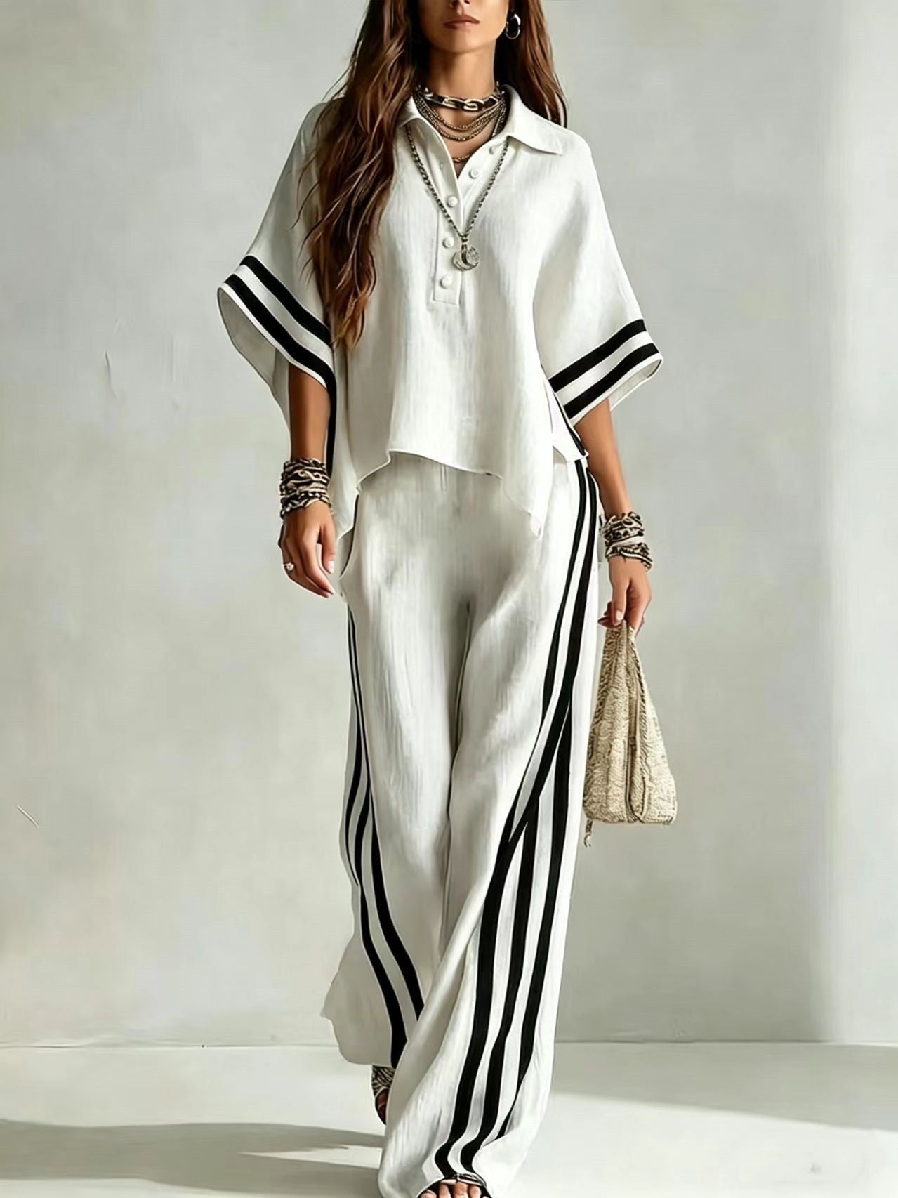 Woman wearing a white outfit with black stripes on a plain background