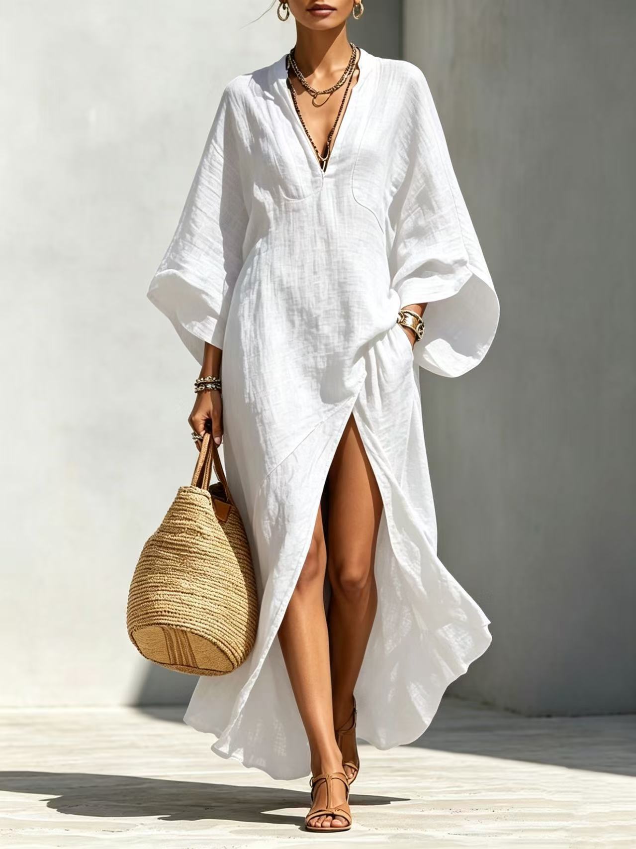 Woman wearing a white cover-up dress holding a woven bag against a plain background