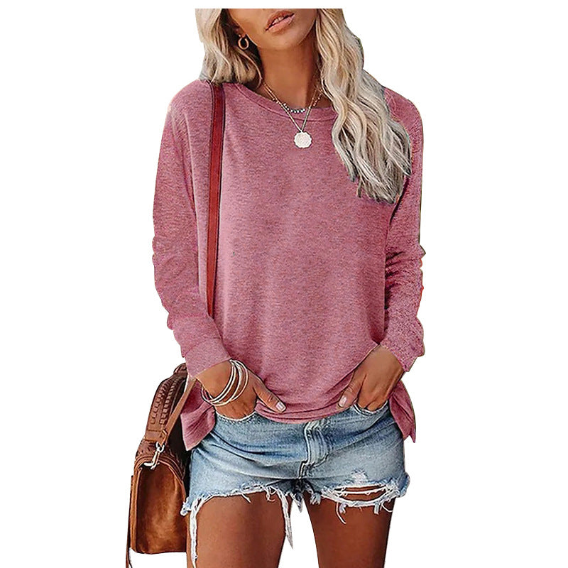 Woman wearing a pink long-sleeve top and denim shorts, holding a brown bag on a white background.