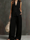Person wearing a black sleeveless top and wide-leg pants against a gray background