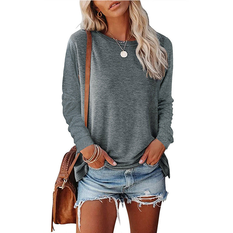 Woman wearing a gray long-sleeve top and denim shorts, holding a brown bag on a white background