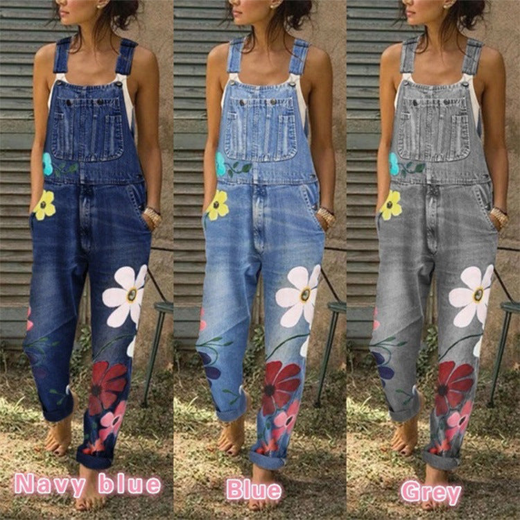 Denim overalls with floral designs in navy, blue, and gray on a person against a wooden background.