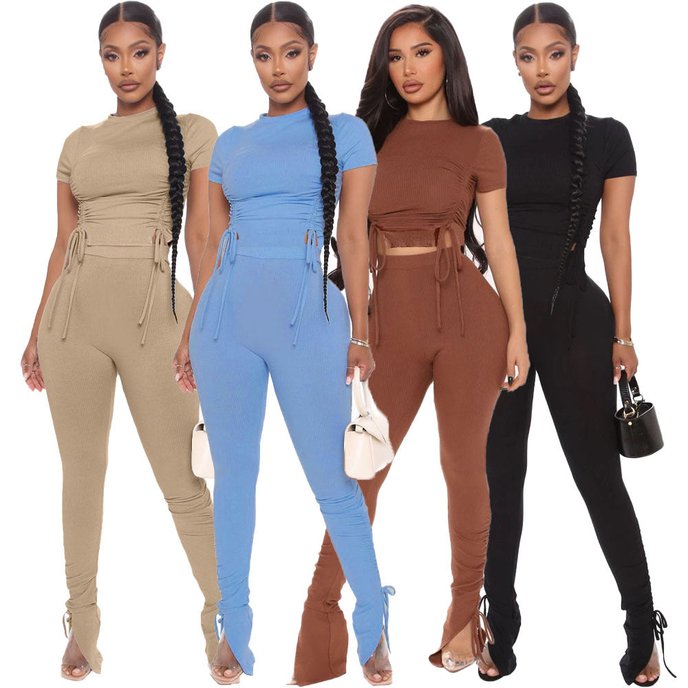 Four women wearing matching jumpsuits in beige, blue, brown, and black on a white background.