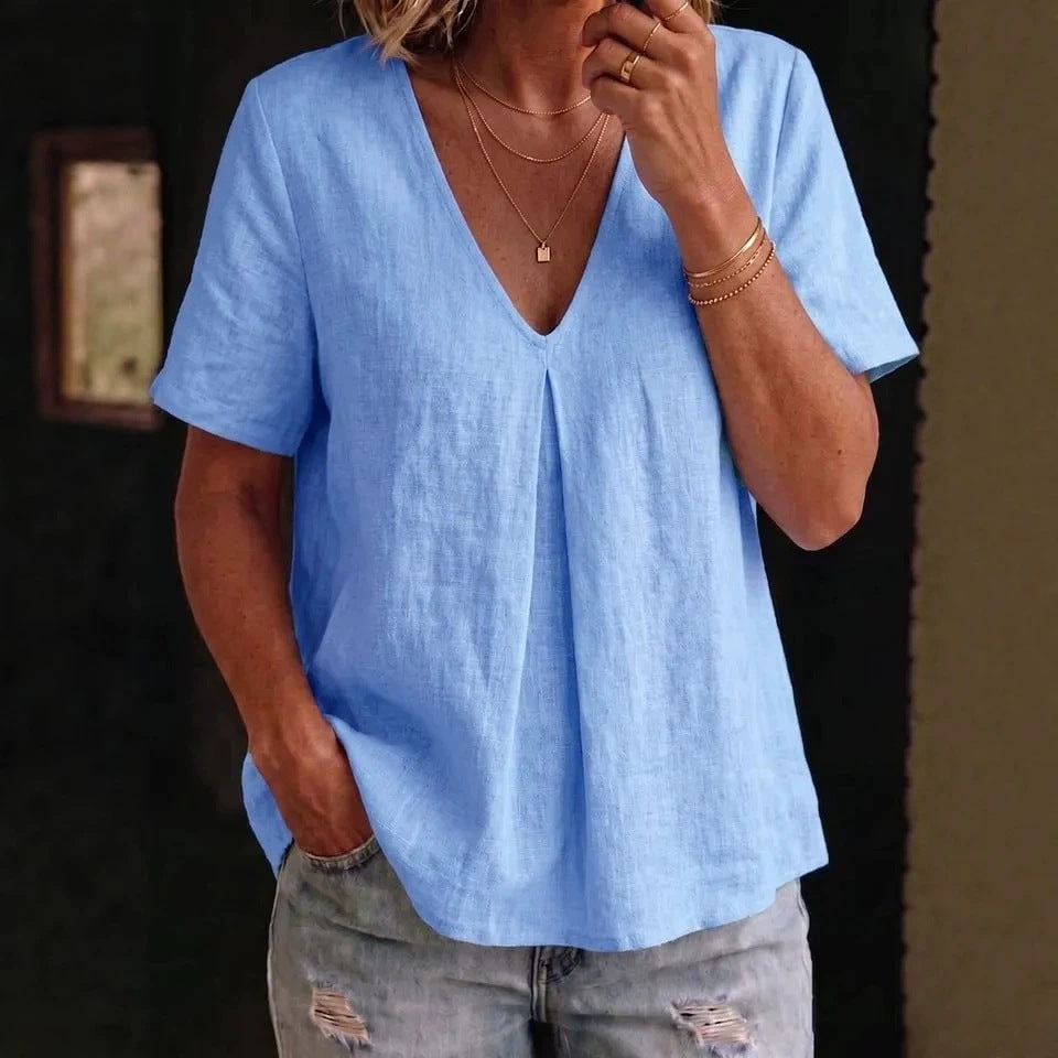 Person wearing a light blue shirt and ripped jeans indoors.