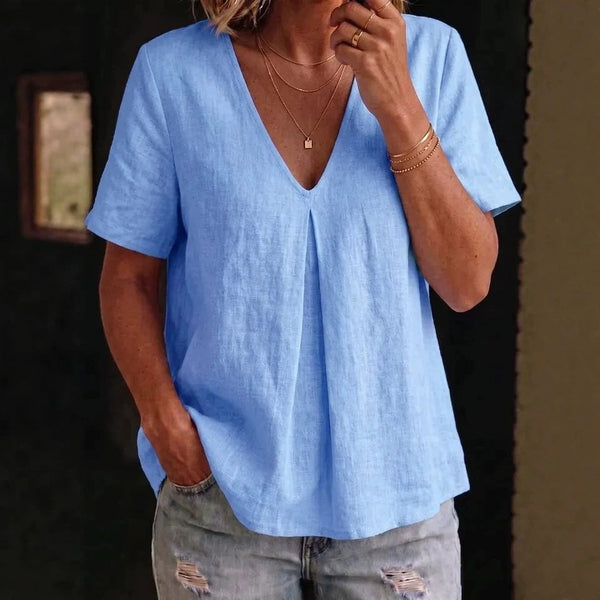 Person wearing a light blue shirt and ripped jeans indoors.