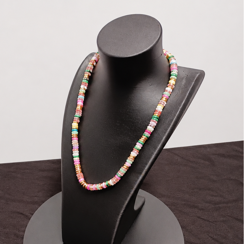 Colorful beaded necklace on a black mannequin bust against a dark surface.