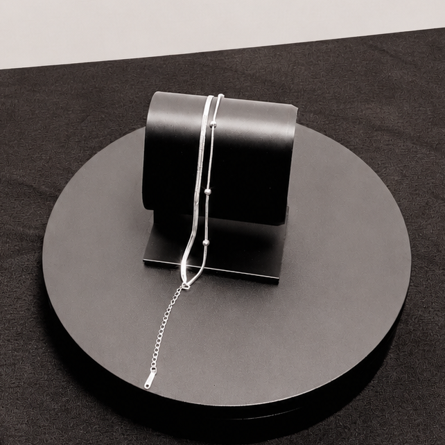 Silver handbag on a black platform with a white background