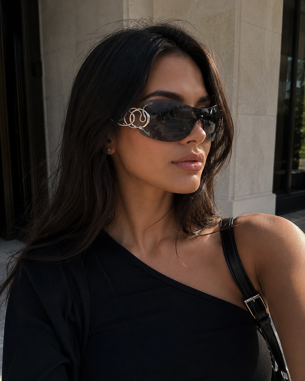 Woman wearing stylish sunglasses with a brand logo, standing outdoors.