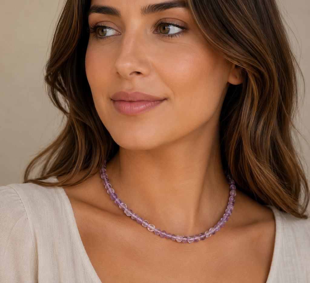 Woman wearing a purple beaded necklace against a neutral background