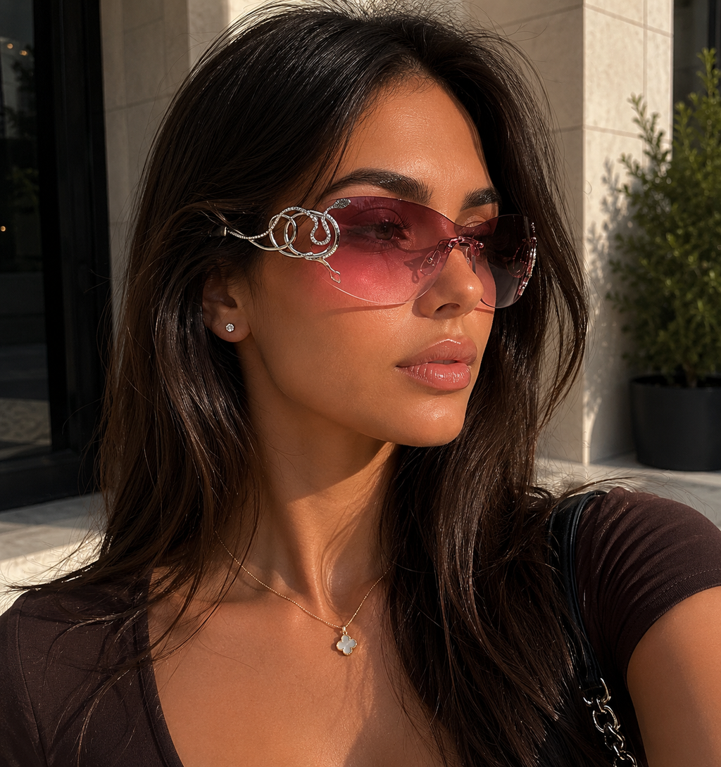 Woman wearing pink sunglasses with a building and plant in the background