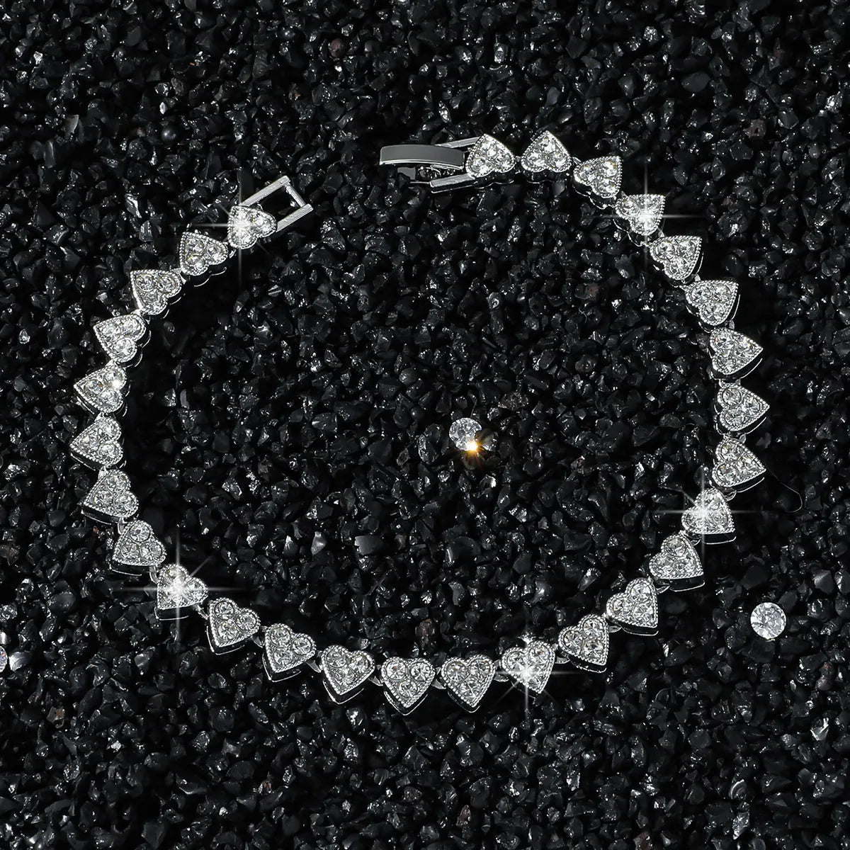 Silver bracelet with heart-shaped diamonds on a black textured background