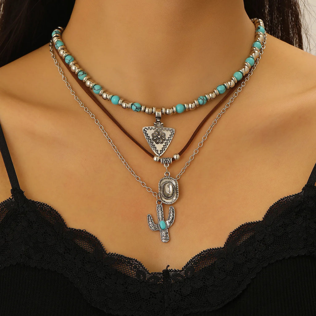 Necklace with turquoise beads and silver pendant on a mannequin wearing a black lace top.
