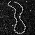 Silver beaded necklace on a black textured background