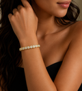 Close-up of a woman's arm wearing a gold bracelet with a blurred background