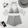Gray checkered bikini set with matching shorts, sunglasses, and a hat on a light background.