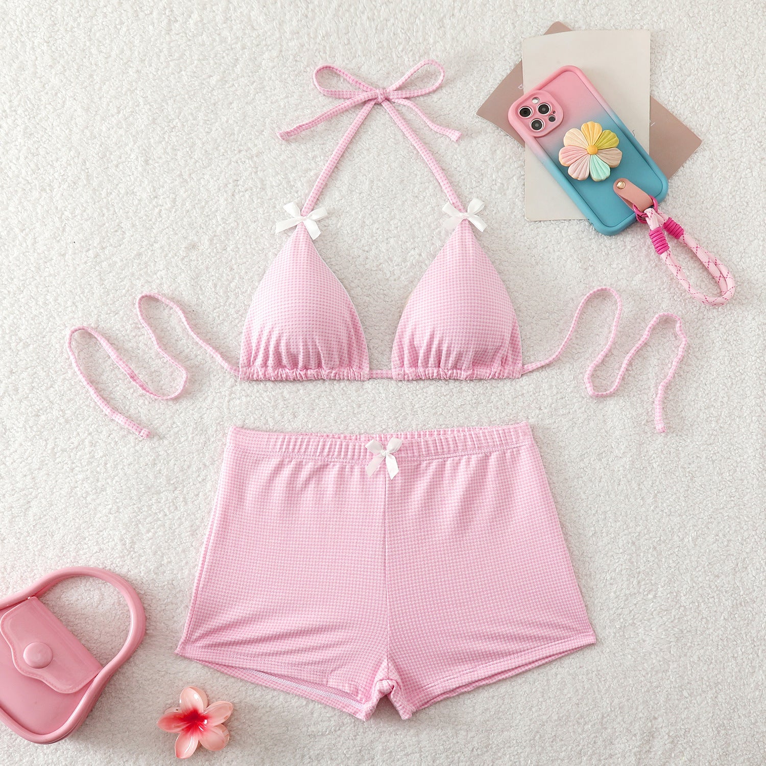 Pink bikini set with matching accessories on a light background
