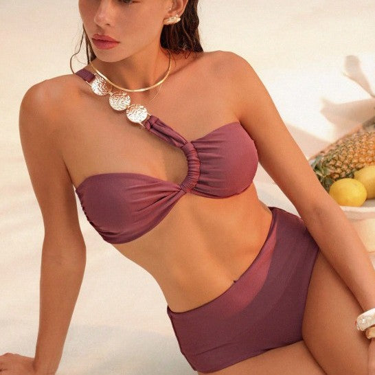 Woman wearing a purple bikini sitting by a table with fruits.
