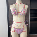 Floral bikini set on a mannequin with a grid for measurement against a neutral background
