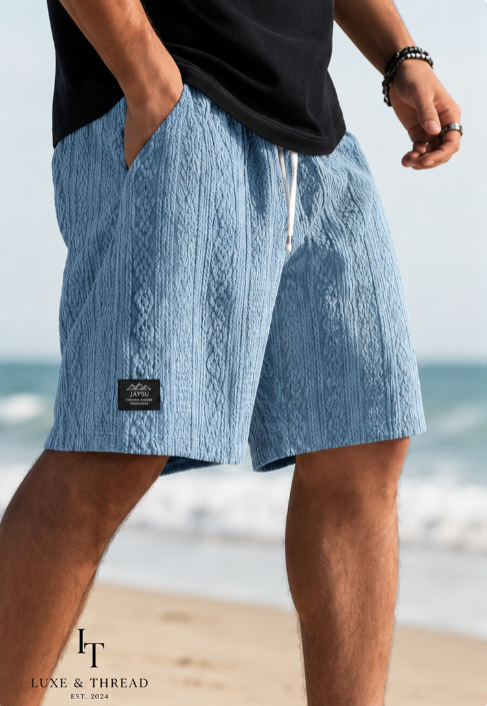 Person wearing blue textured shorts with a blurred beach background