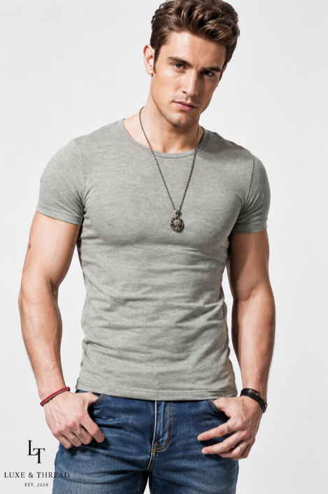 Man wearing a gray t-shirt and blue jeans with a necklace on a white background