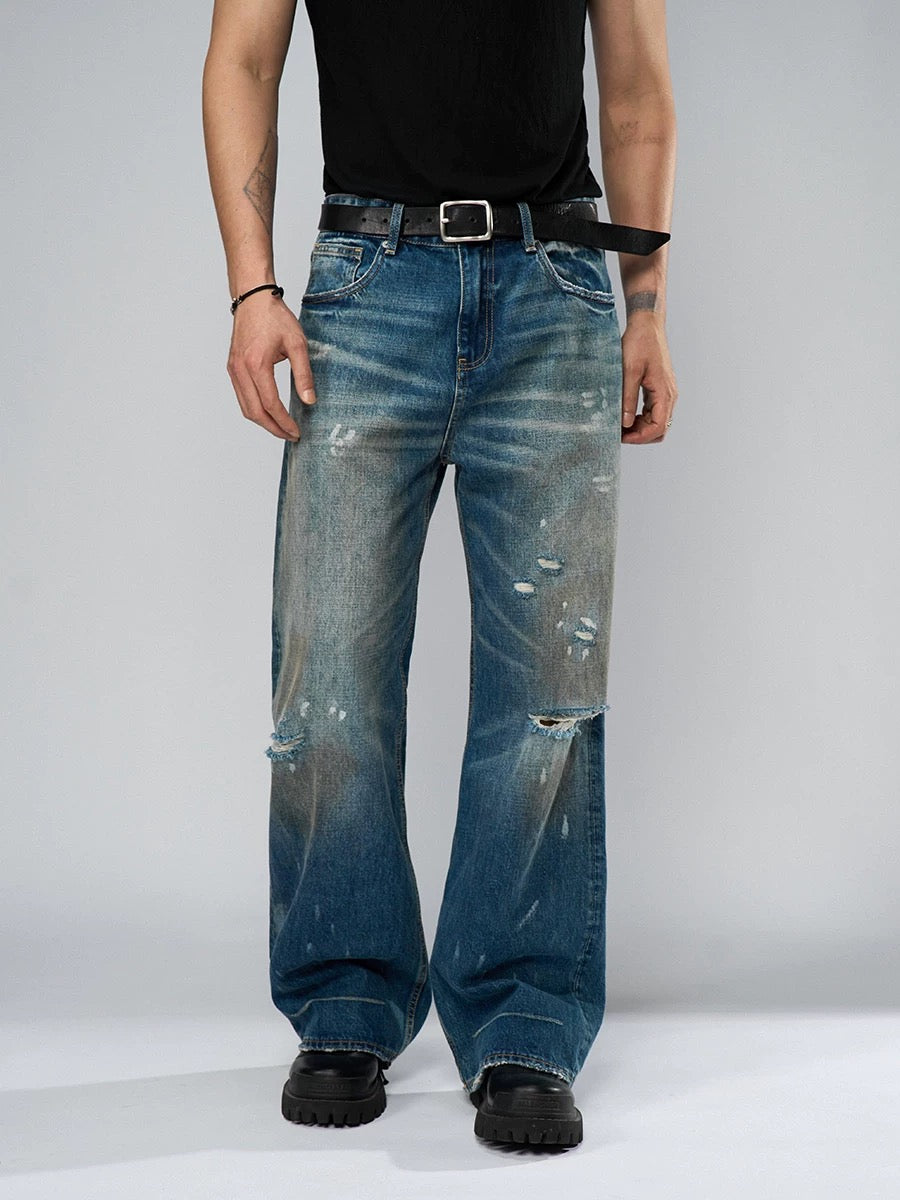 Person wearing distressed blue jeans on a plain background