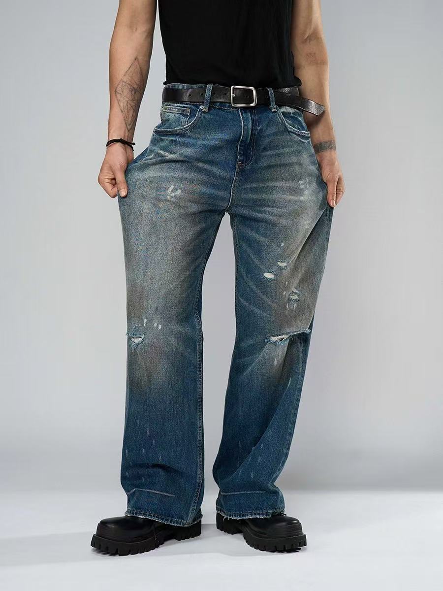 Person wearing distressed blue jeans on a plain background