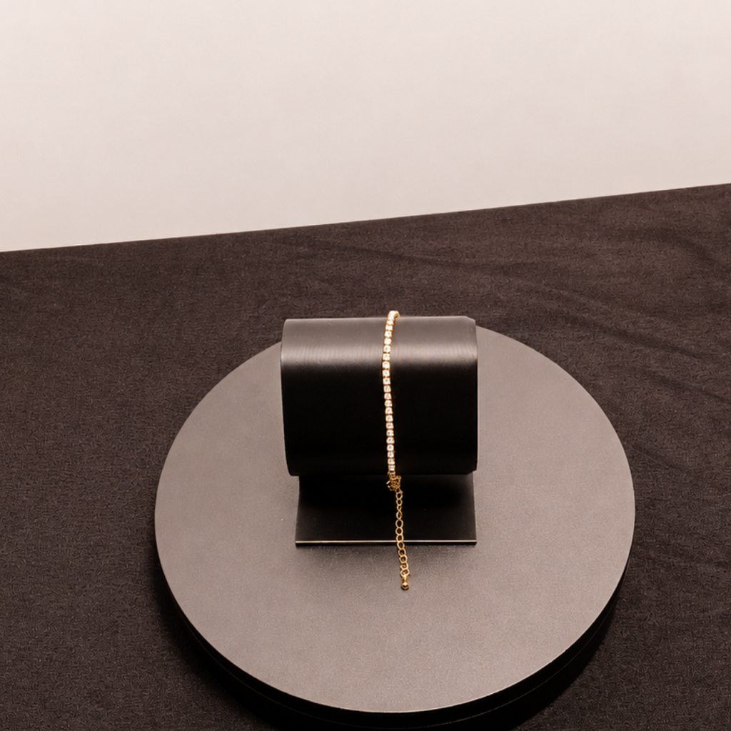 Gold bracelet on a black jewelry stand against a dark surface
