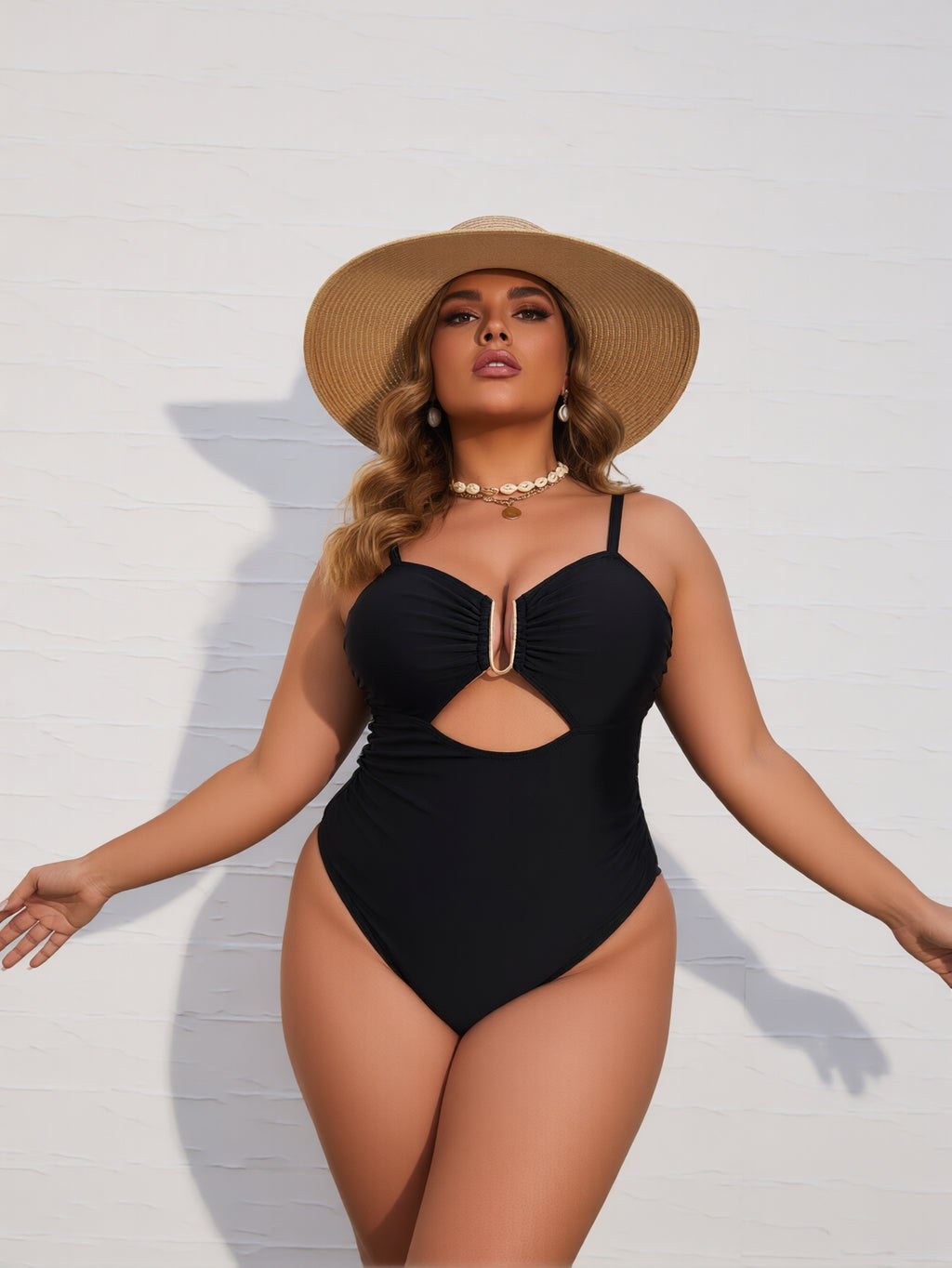 Woman wearing a black swimsuit and straw hat against a white background
