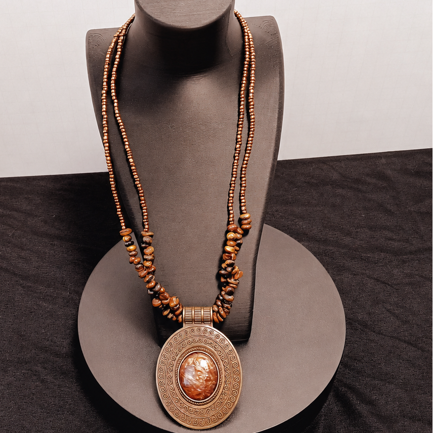 Necklace with a large pendant on a gray mannequin head against a neutral background