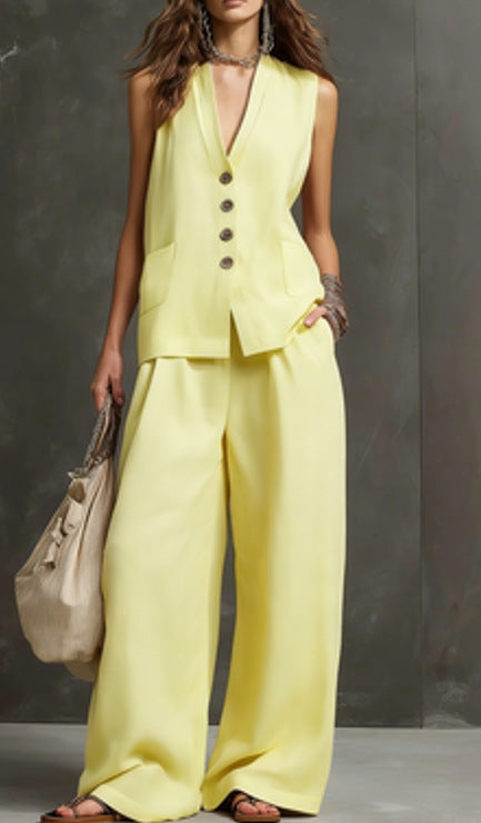 Woman wearing a yellow suit with wide-leg pants against a gray background