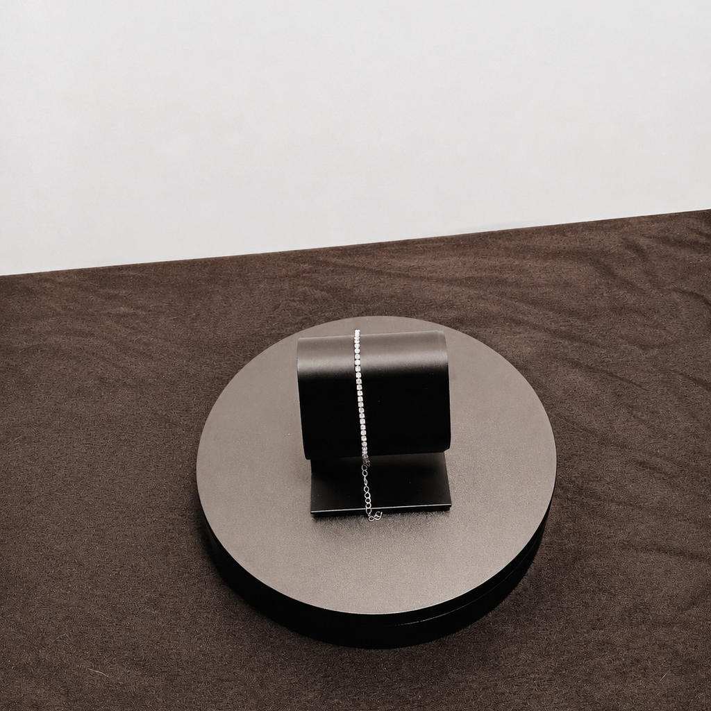 Silver necklace on a round metallic stand with a white background